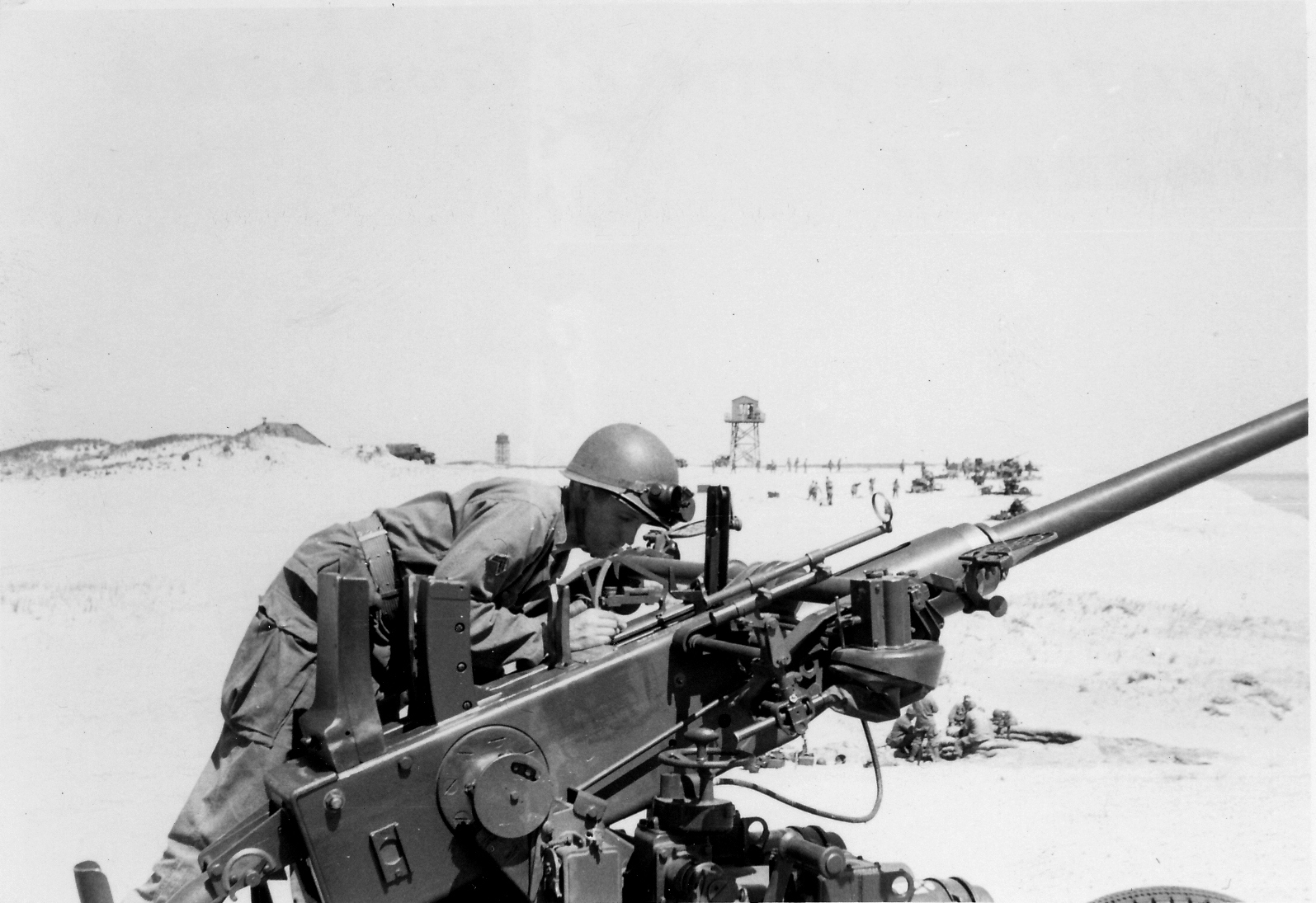 A U.S. Army anti-aircraft gunner seated at a 40mm automatic cannon, checking its elevation.
